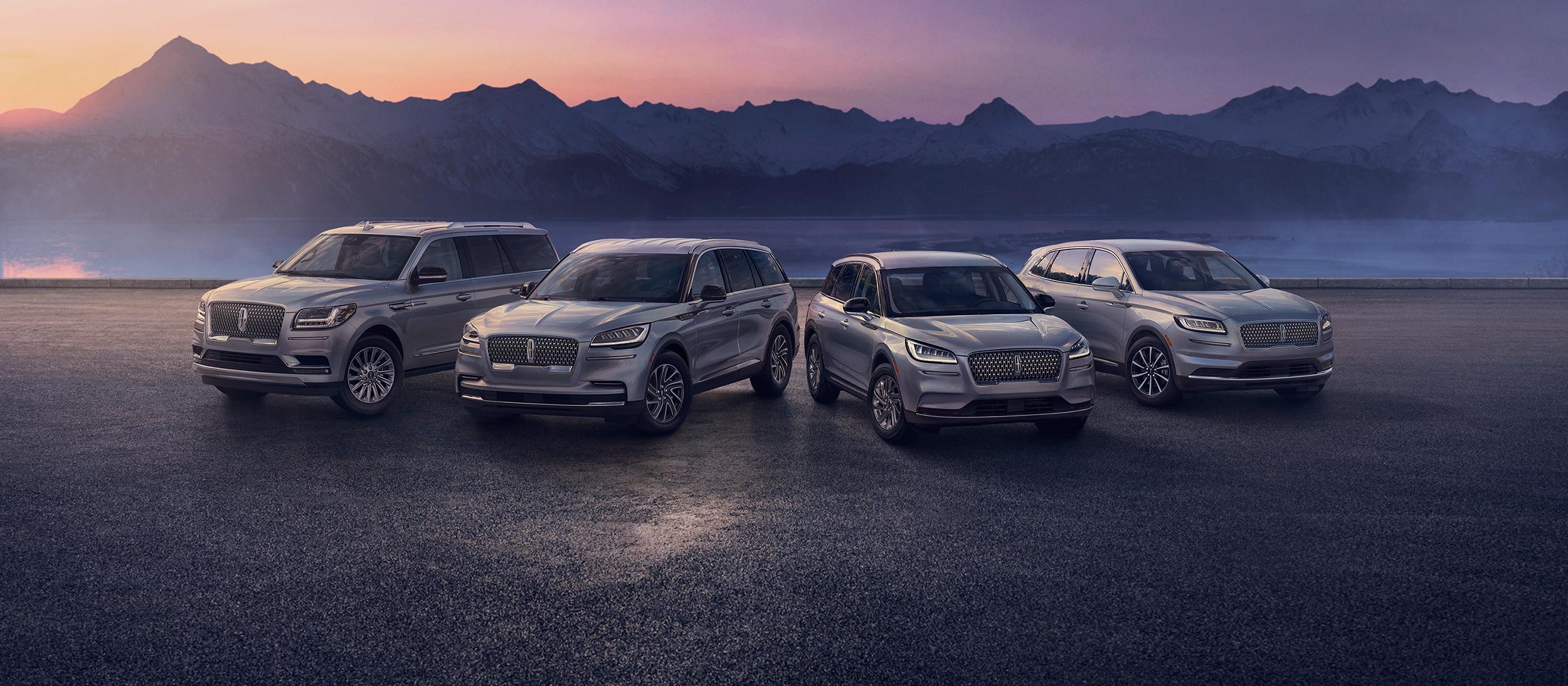 A group shot showcasing Lincoln SUVs parked in front of sunset soaked mountains