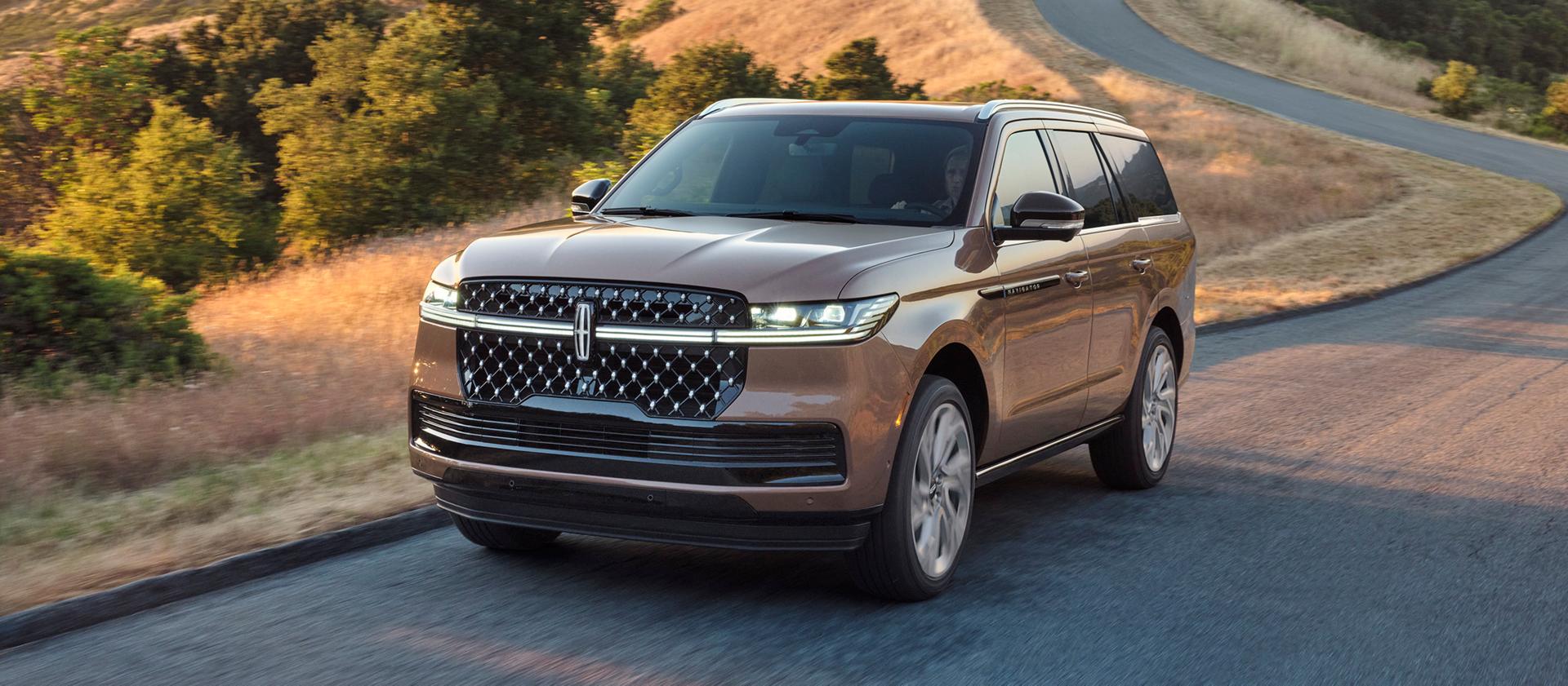 The 2025 Lincoln Navigator driving down a sunset road.
