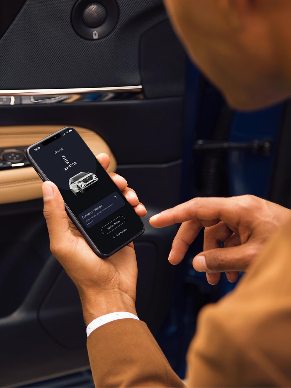 A man holding a phone viewing the Lincoln Rewards App