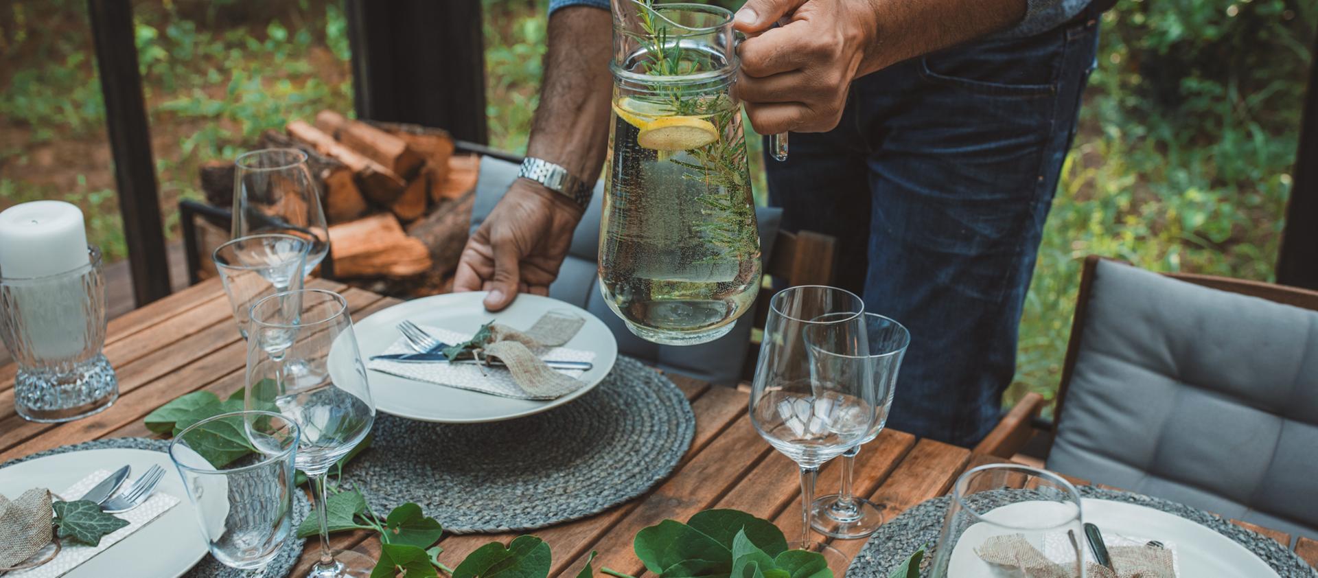 A man sets an outdoor dining table in anticipation of his guests