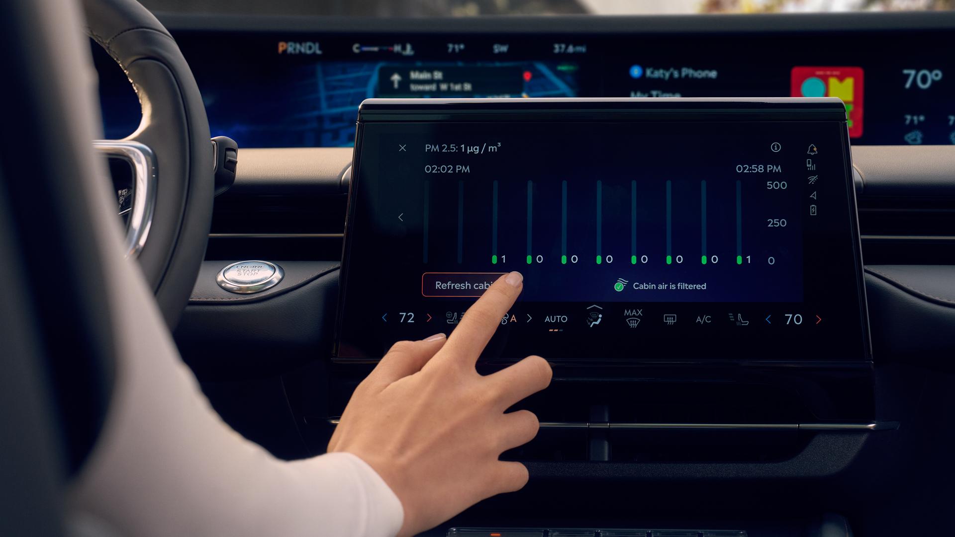 A person uses the center touch screen to control Auto Air Refresh