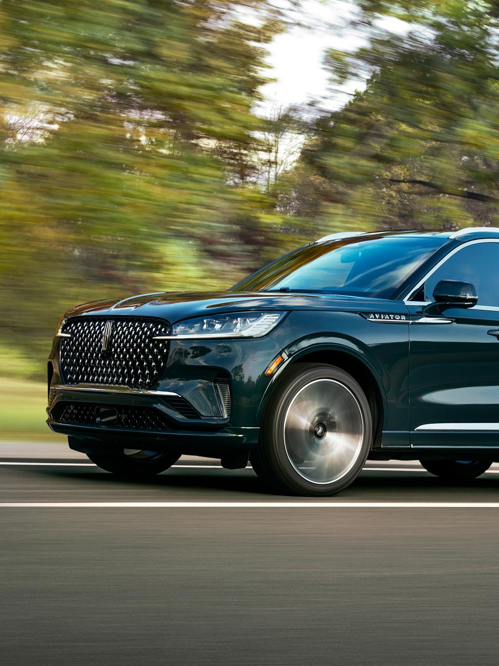 A 2025 Lincoln Aviator® is being driven on a winding tree-lined road