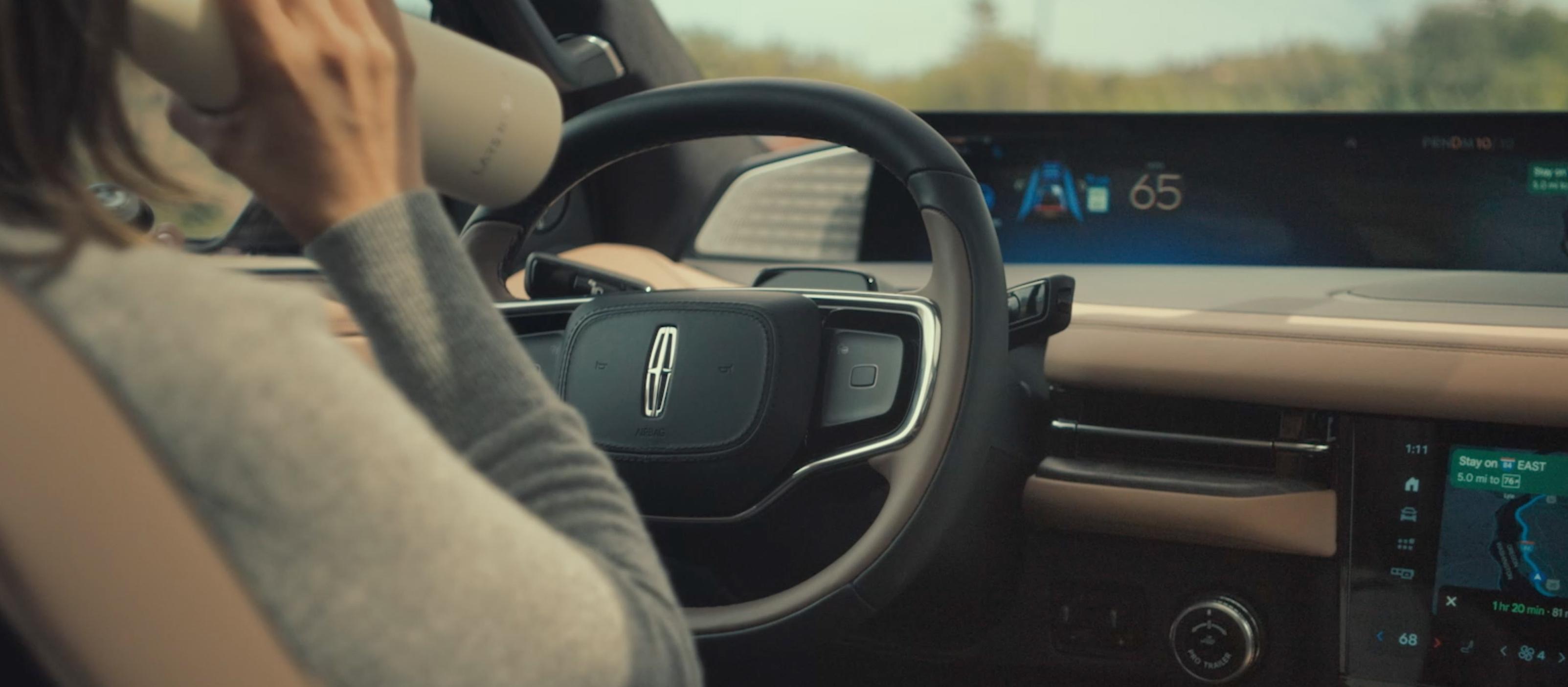 A woman drinks from a water bottle while driving a 2026 Lincoln Black Label Navigator hands-free