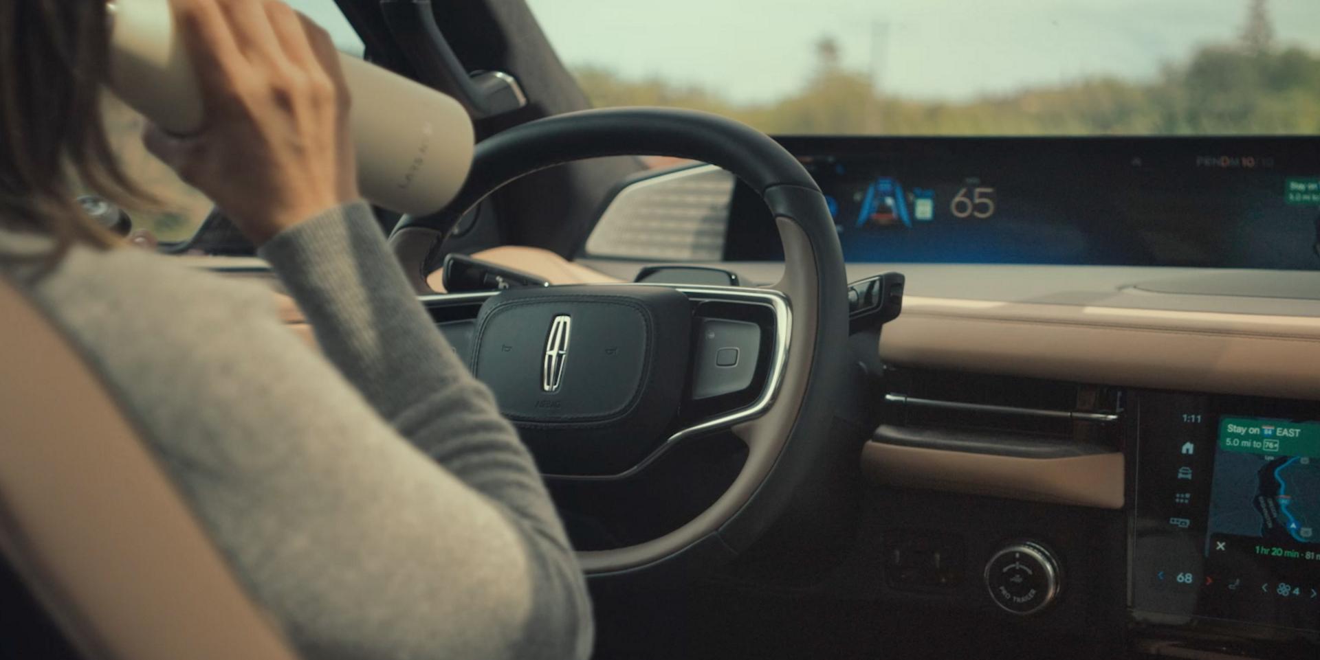 A woman drinks from a water bottle while driving a 2026 Lincoln Black Label Navigator hands-free