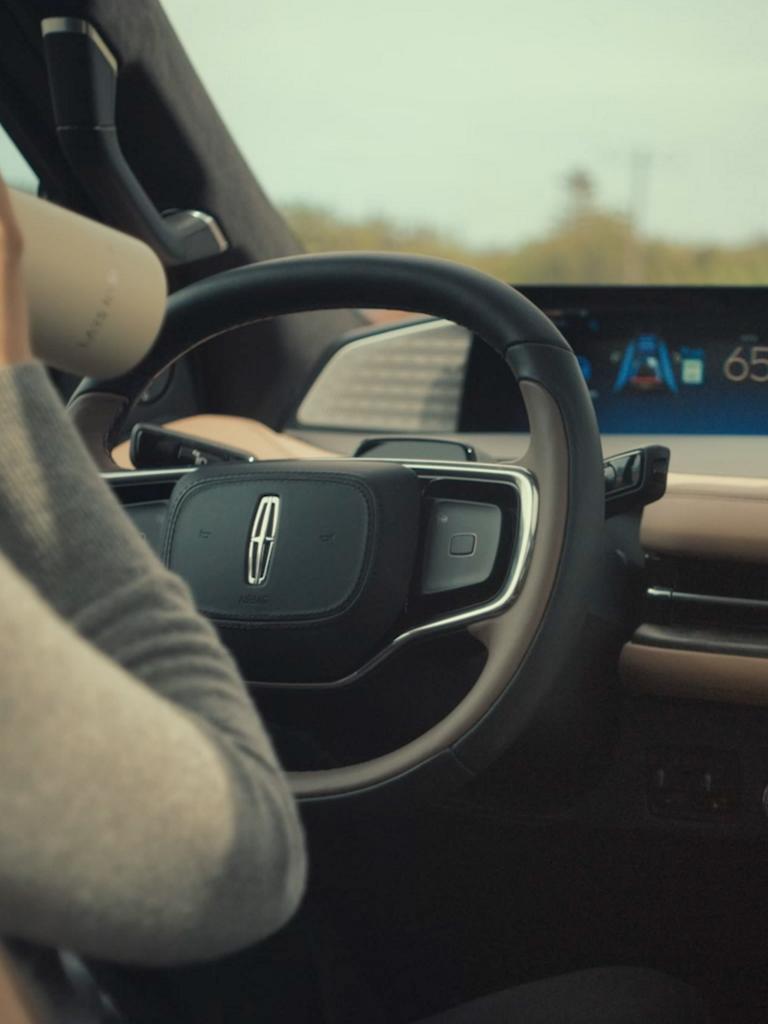 A woman drinks from a water bottle while driving a 2026 Lincoln Black Label Navigator hands-free