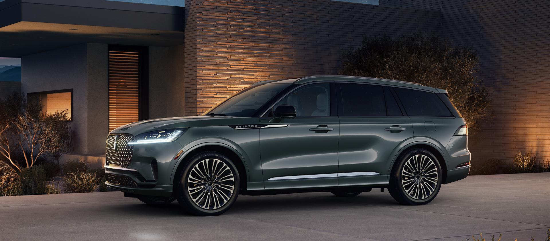 A 2027 Lincoln Aviator® Black Label™ SUV is parked next to a modern home at night