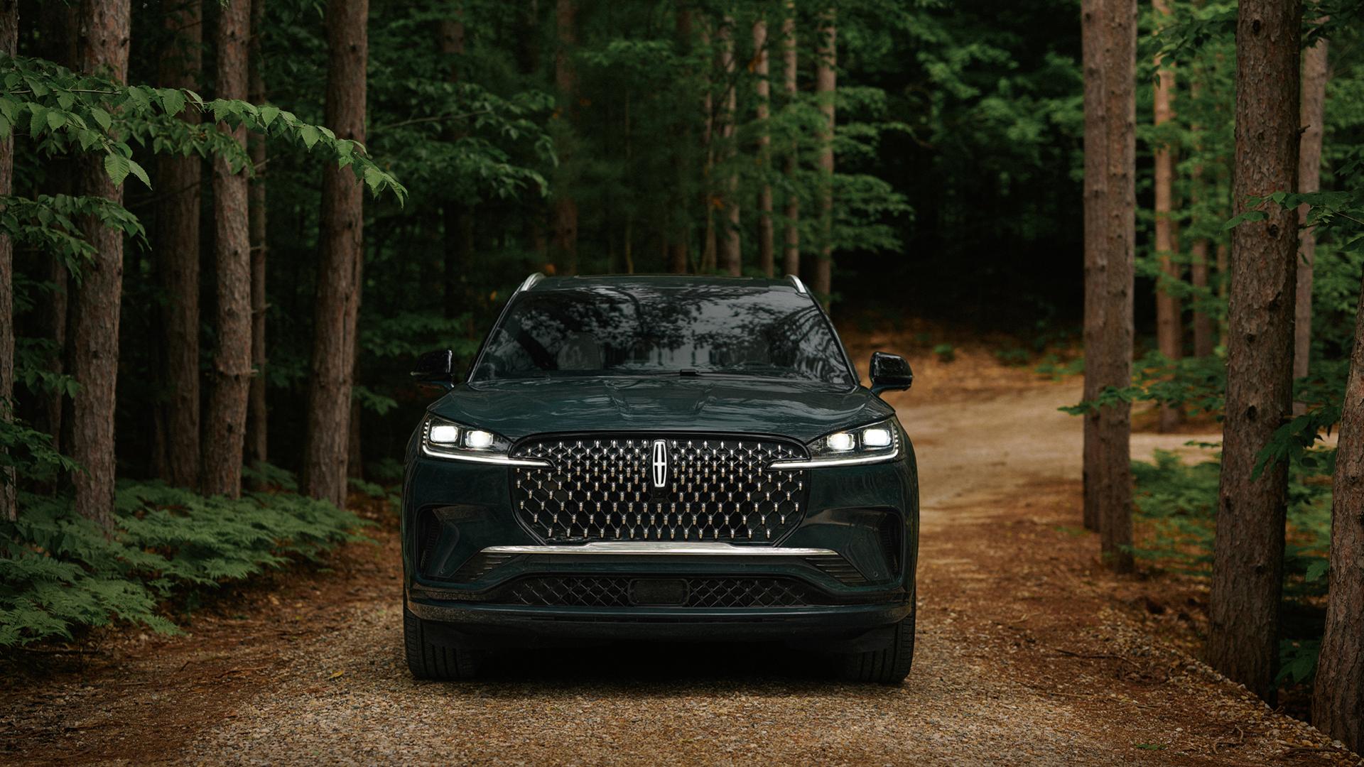 A 2027 Lincoln Aviator® SUV is being driven on a remote forest roadway