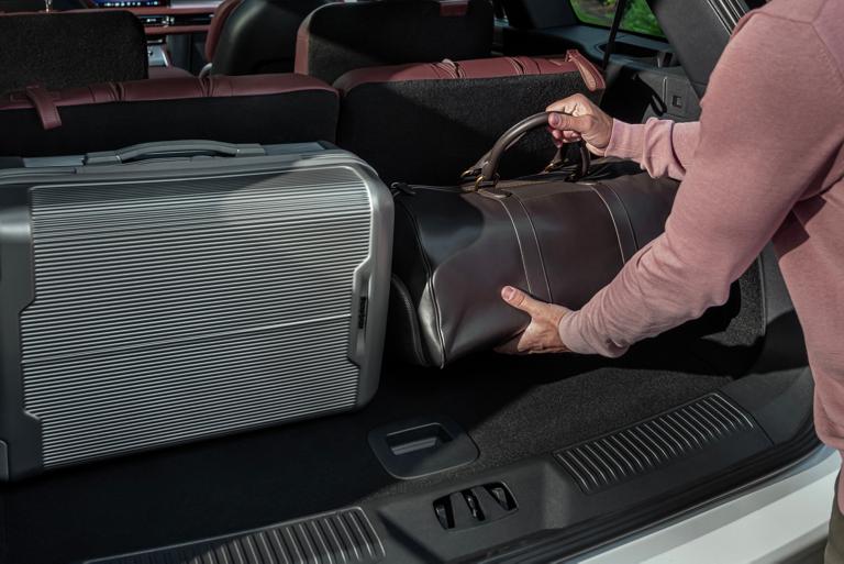 A person loads a leather bag into the rear cargo area of a 2026 Lincoln Aviator® SUV