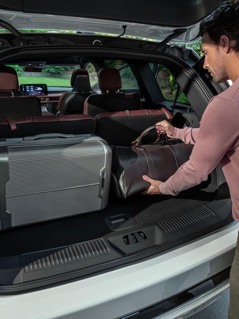 A person loads a leather bag into the rear cargo area of a 2026 Lincoln Aviator® SUV
