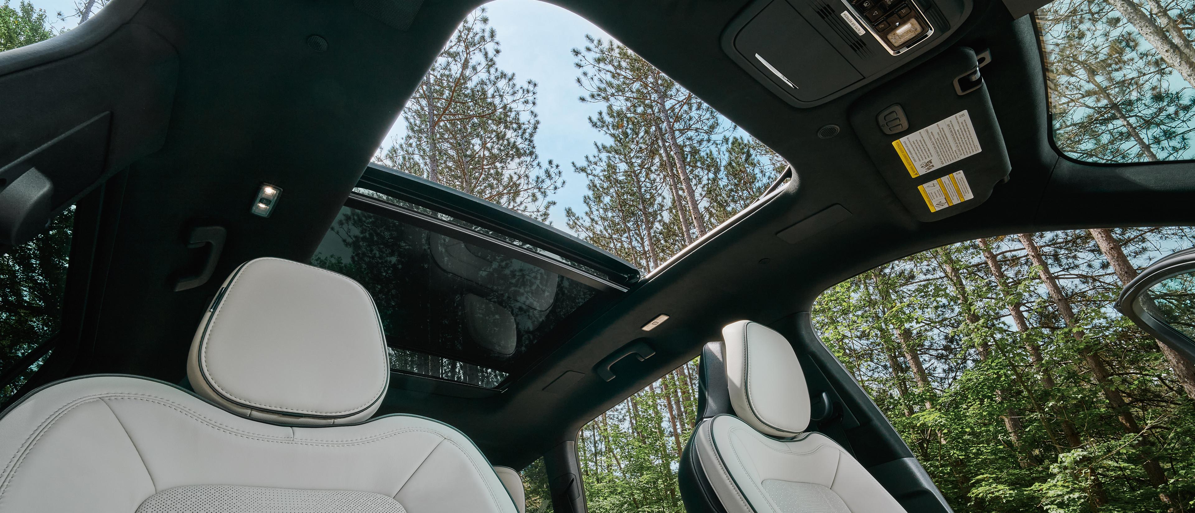 An interior view of a 2027 Lincoln Aviator® SUV looking up through the panoramic Vista Roof®