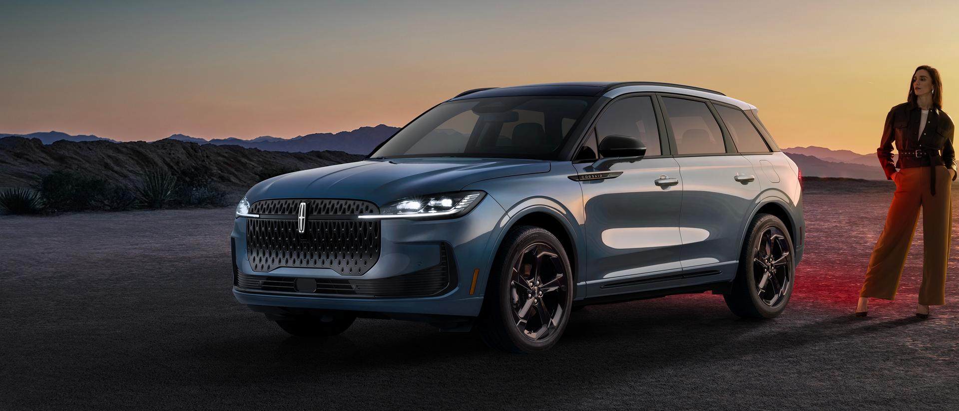 A stylishly dressed woman standing next to a 2027 Lincoln Corsair® Hybrid parked in a dramatic desert landscape